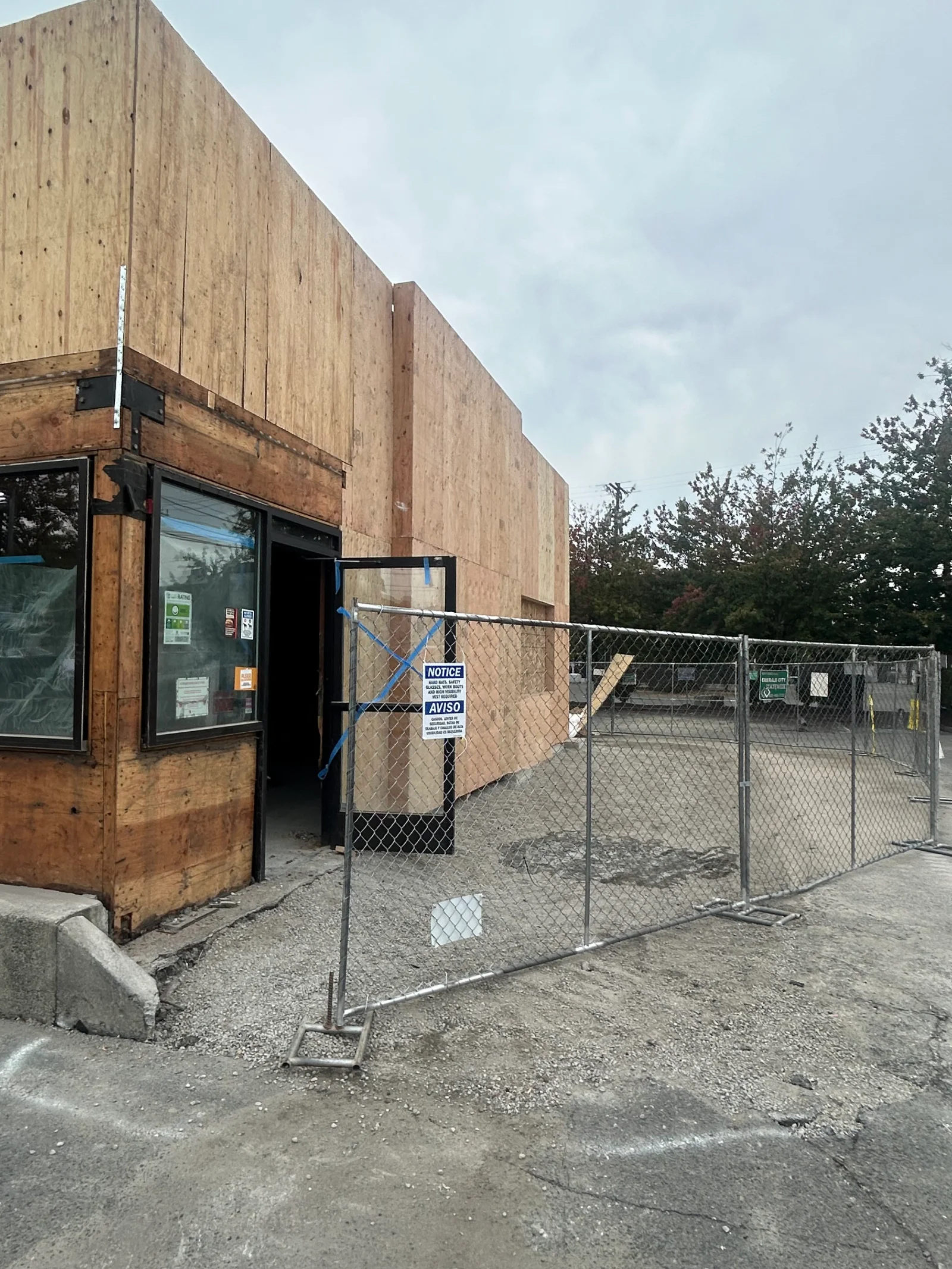 Commercial building with new plywood sheathing, wooden framing, and temporary chain-link fencing