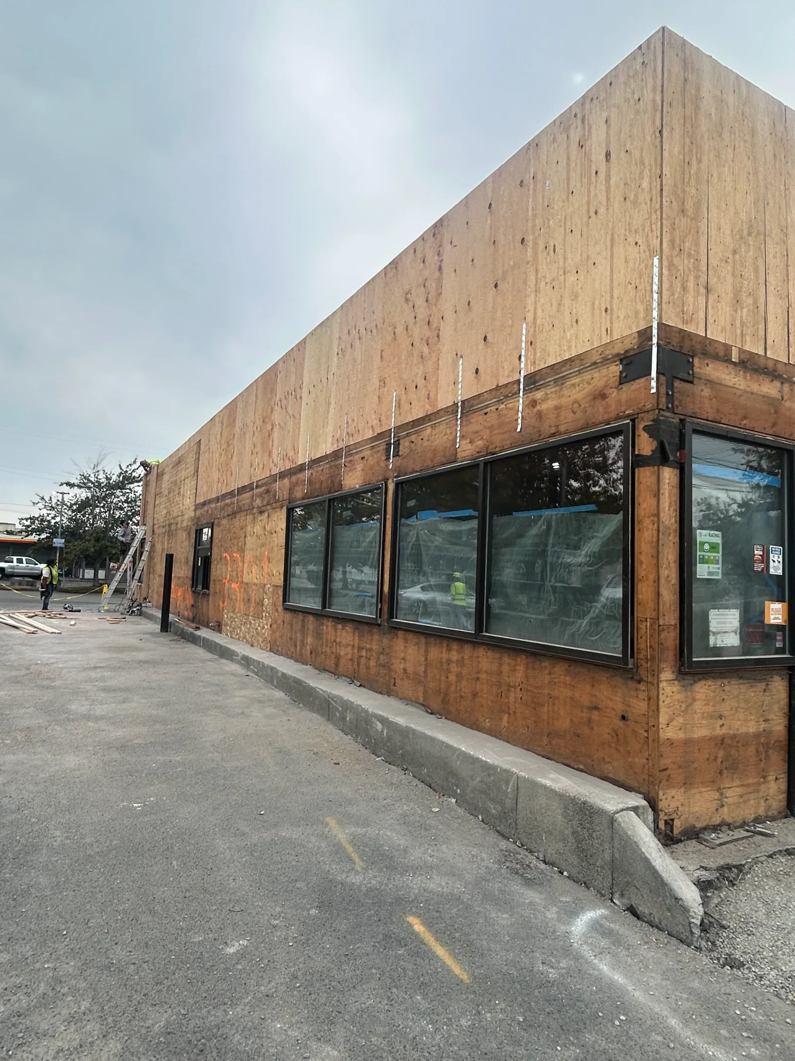Commercial building with new plywood sheathing, metal flashing, and large storefront windows during renovation
