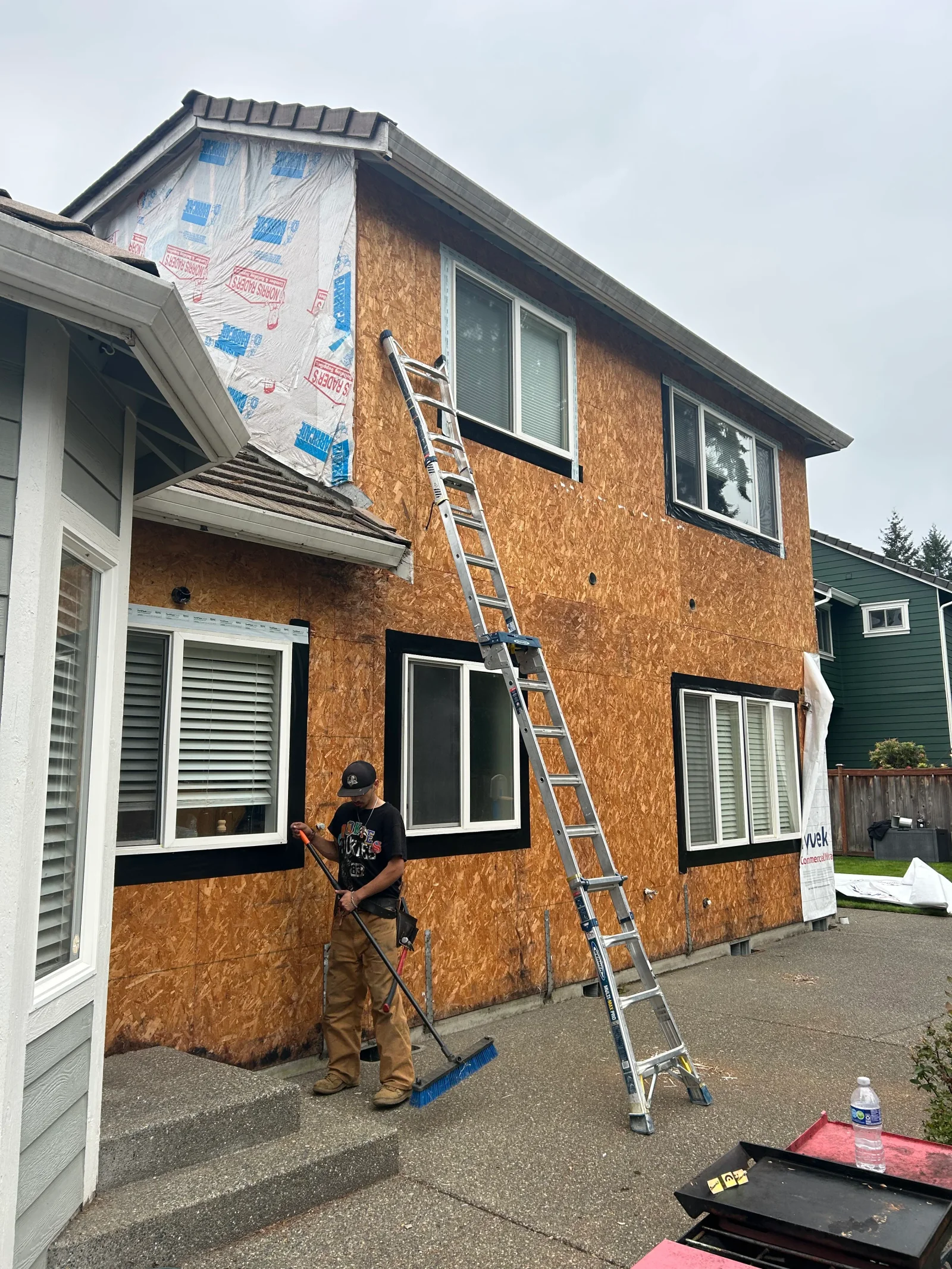 Brick home exterior with OSB sheathing, new windows, and weather barrier installation during renovation