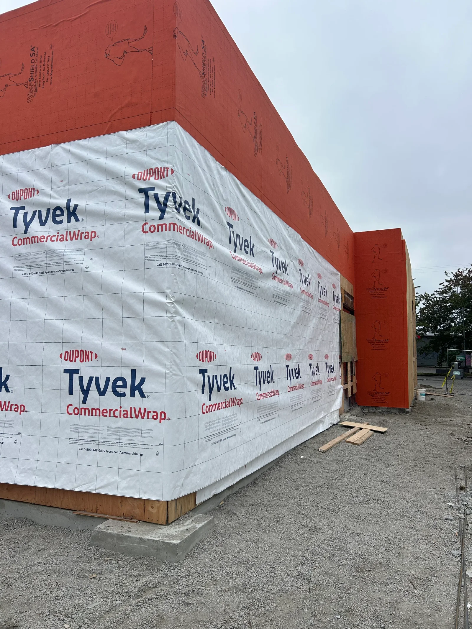 Tyvek CommercialWrap weatherproofing installed on building exterior with red metal frame