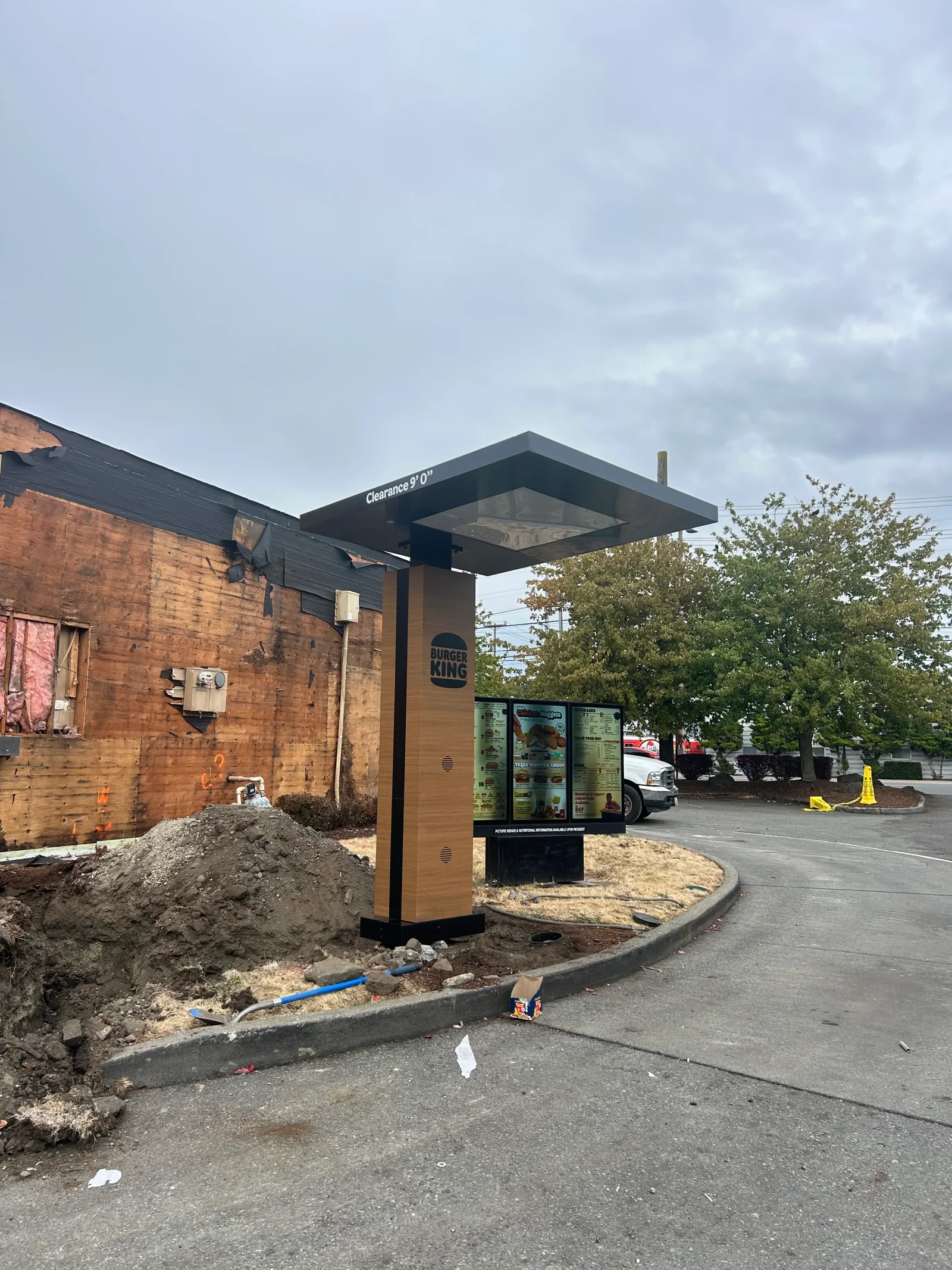 Black metal canopy with wood column over drive-thru window, LED lighting, concrete curbing