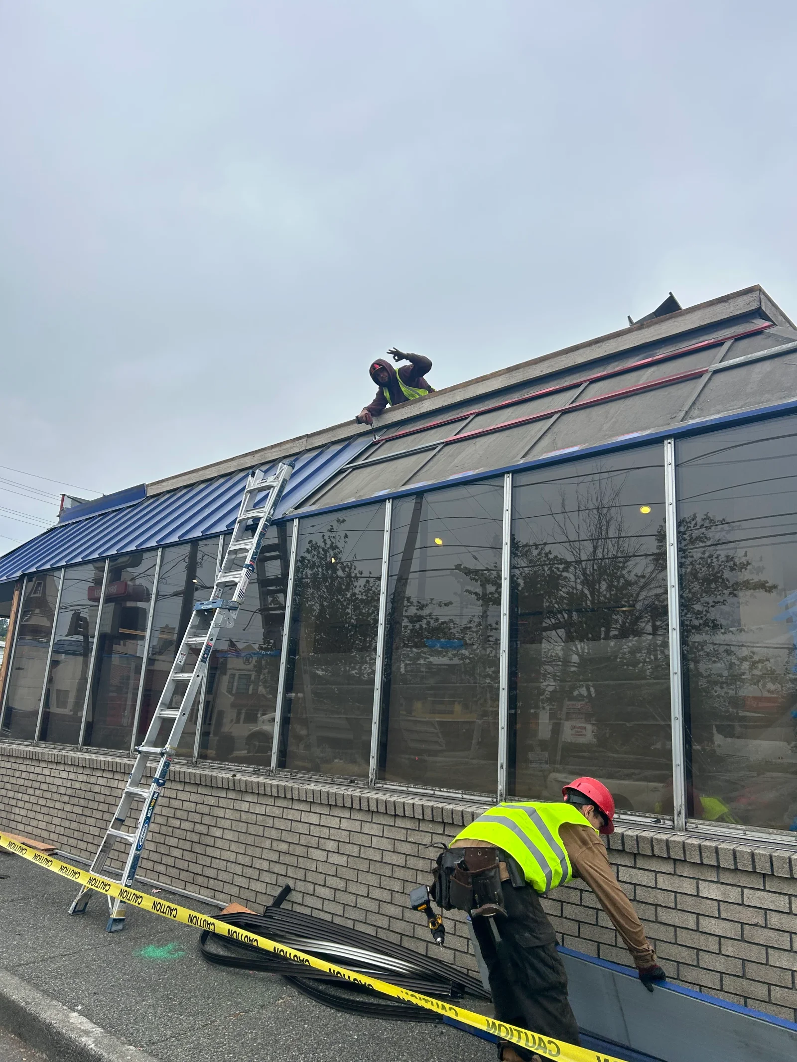 Metal roof installation with blue standing seam panels and gray underlayment on commercial building